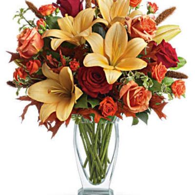 Roses, lilies and oak leaves create a fantasy of fall flowers. Send this tall, elegant arrangement to wish someone a happy autumn or joyous Thanksgiving. The warm color palette and Couture Vase make a stylish seasonal statement.
Orange, dark orange and red roses blend with orange asiatic lilies, green salal and pitta negra. Subtle seasonal elements include dried oak leaves and millet.