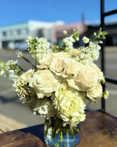 <p>Creamy white roses fragrant stock lush hydrangeas elegantly designed in a cylinder.</p>