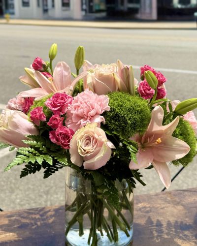 <p>Pink roses, lilies, spray roses, carnations and greens designed in a glass cylinder.</p>