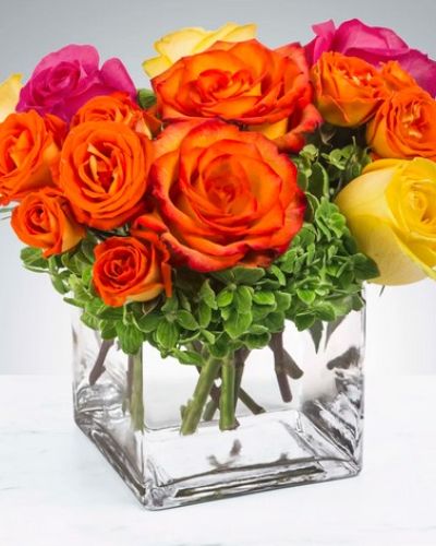 <p>Pink, yellow and orange roses come together with green hydrangeas for a bright cube of sunshine.</p>