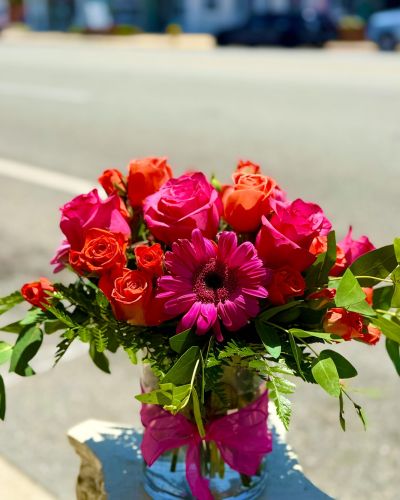 <p>Hot pink roses electric orange spray roses and popping pink Gerbers designed in a lush cylinder.</p>