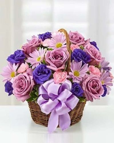 Hand-designed in a charming handled basket and accented with a satin ribbon, this Basket of Blossoms is sure to make her smile. This beautiful arrangement is filled with roses, lisianthus and daisies in rich shades of purple and lavender.