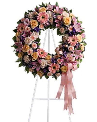 <div id="mark-1" class="m-pdp-tabs-marketing-description">Family and friends will recollect how special their loved one was with this gentle ring of pastel blooms. Highlighted with a pink satin ribbon, it is a lovely reminder of sweet memories and beautiful times shared.</div>
<div id="desc-1">
<ul>
<li>Peach roses, gerberas and carnations, pink asiatic lilies and lisianthus, along with purple limonium and lavender larkspur – accented by greens woven throughout – are presented on an easel-mounted wreath, ideal for a memorial occasion.</li>
</ul>
</div>