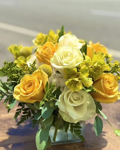<p>White hydrangeas yellow and white roses yellow alstroemeria designed in a glass cube</p>