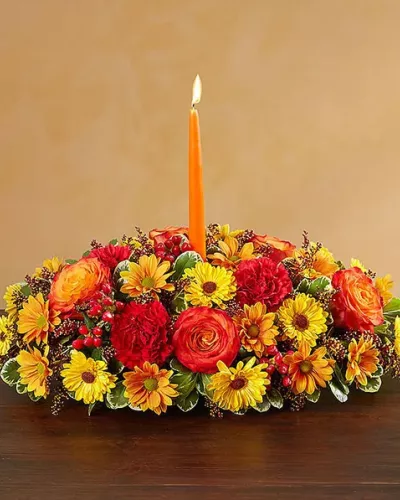 Send your warmest wishes to the people you love with our colorful autumn centerpiece. This traditional table arrangement is designed with radiant blooms and finished off with an orange taper candle to cast a cozy glow over seasonal gatherings.